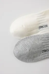 Close-up detail of ribbed cotton mid-tube socks in white and grey with letter print.