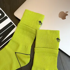 Close-up of neon green mid-calf crew socks featuring distinctive script embroidery on ribbed cuffs.