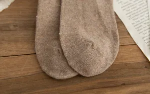 Gros plan de chaussettes en laine tricotées marron confortables sur surface en bois.