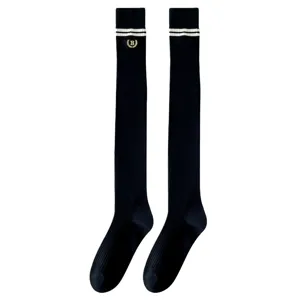 Schwarze Overknee Socken mit weißen Streifen und gesticktem Emblem im britischen Schulstil.
