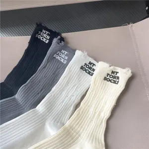 Vista dettagliata di calze slouch a costine con fori strappati e ricamo personalizzato.
