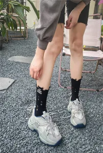Primo piano dettagliato di calze nere strappate con testo e sneaker chunky alla moda fuori.