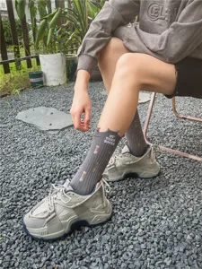 Calze grigie alla moda con lettere ricamate e fori strappati per un look streetwear femminile.