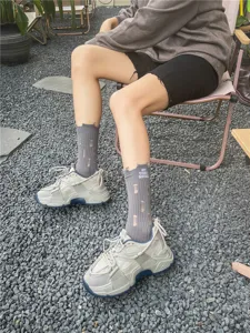 Calzini grigi ricamati da donna con effetto strappato abbinati a sneakers chunky casual.