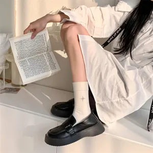 Vista dettagliata di calzini bianchi da donna con ricamo e mocassini neri platform.