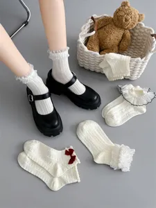 Detailed view of women white lace ruffle JK Lolita socks detail shot with bow accents on grey background