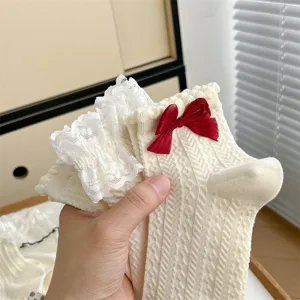 Close-up of white JK style lace socks with red bow, showing delicate fabric texture.
