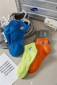 Primo piano di calzini corti in cotone colorato con simpatiche lettere ricamate per uso quotidiano.