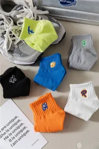 Dettaglio di calzini in cotone colorati con lettere ricamate per un look casual e moderno.