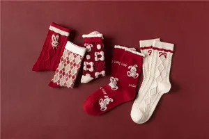 Gros plan de chaussettes d'hiver rouges en coton avec jolies broderies de lapins et noeuds.