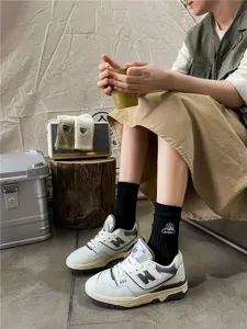 Detail shot of black mid-tube cotton socks with camping snow mountain embroidery worn in scene.