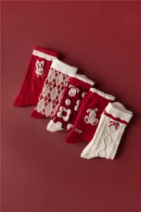 Détail de chaussettes d'hiver rouges avec des motifs de lapin et nœud pour les fêtes.