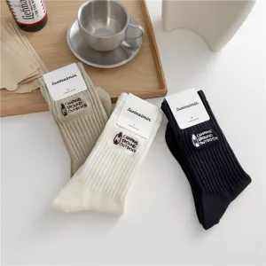 Detail shot of vintage camping embroidered crew socks featuring paper tags and soft cotton material.