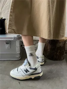 Close-up of white ribbed cotton socks with camping mountain embroidery, outdoor style.