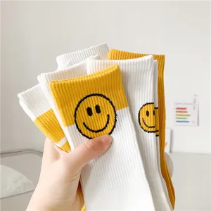 Vue détaillée de chaussettes mi-hautes jaunes et blanches pour femmes avec visage souriant et côtes.