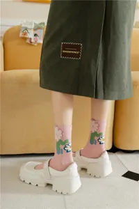 Chic floral mid-calf socks paired with white platform shoes and green corduroy skirt detail.