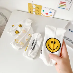 Chaussettes mi-hautes blanches en coton avec imprimés de visages souriants jaunes et lettres.