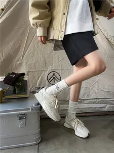 Detail shot of retro outdoor camping embroidered mid-tube cotton socks paired with stylish sneakers.