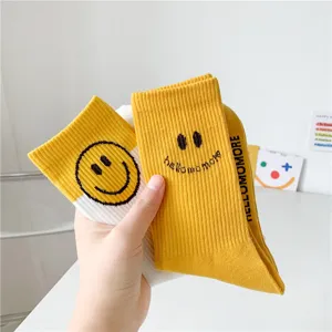 Vue détaillée de chaussettes mi-mollet en coton jaune et blanc avec un joli visage souriant.