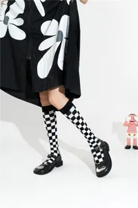 Detailaufnahme von schwarz-weißen Karosocken kombiniert mit Mary Jane Schuhen und Kleid.