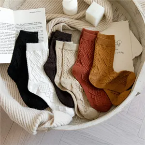 Detailed view of women's cable knit argyle wool blend socks in warm cozy lifestyle flat lay