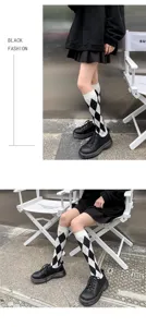 Gros plan de chaussettes hautes à motif argyle noir et blanc, mettant en valeur la texture tricotée.