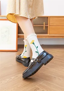 Detailansicht japanischer Retro-Wadenstrümpfe in Weiß mit gelber Blumenstickerei und Rüschen.