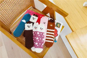 Detailansicht kuscheliger flauschiger Wintersocken mit süßen Tierdesigns auf einem Holzstuhl.