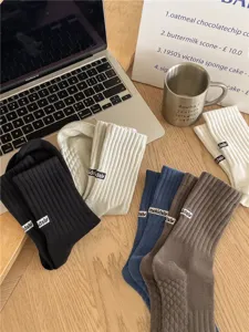 Close-up detail shot of casual ribbed crew socks featuring woven labels in multiple colors.
