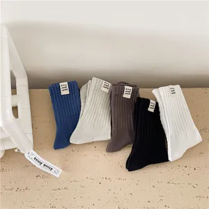 Chaussettes montantes en coton côtelé unies pour hommes, avec de petites étiquettes tissées au poignet.