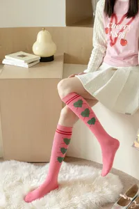Chaussettes hautes roses style collège français avec motifs de cœurs verts et bords rayés.