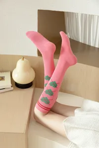 Chaussettes hautes roses de style collège français avec adorables cœurs verts et rayures.