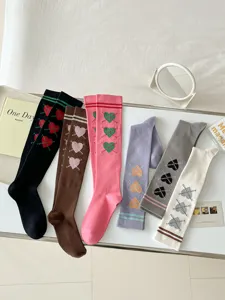 Gros plan de chaussettes hautes style collège en tricot avec motifs de cœurs et colorées.