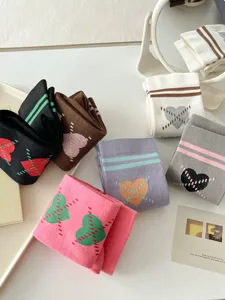 Vue détaillée de chaussettes hautes style préppy avec jolis motifs de cœurs et rayures.