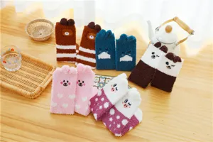 Detailansicht süßer Cartoon-Tier Korallenfleece-Socken auf einem gemütlichen Holztisch