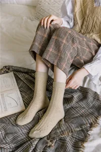 Close-up detail of cozy knit wool-blend socks with retro diamond pattern in beige color.
