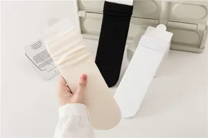 Vue de détail de chaussettes unies mi-hautes présentées en beige, en noir et en blanc.