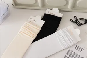 Vue détaillée de chaussettes unies décontractées en beige, noir et blanc. Texture tricotée.