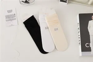 Vue détaillée de chaussettes unies mi-hautes en noir, blanc et beige, douce et soignée.