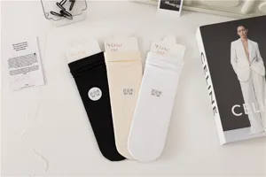 Vue détaillée de chaussettes unies en coton noir, beige et blanc soigneusement présentées.