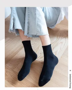Detail shot of black cotton mid tube socks in lifestyle setting on wooden floor background