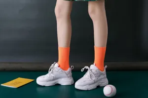 Nahaufnahme von leuchtend orangefarbenen Rippstrick-Socken mit trendigen klobigen Turnschuhen.