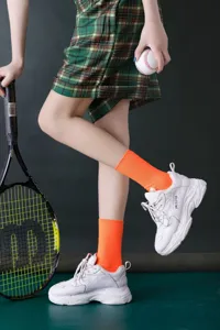 Detailaufnahme von neonorangen gerippten Damen-Mittelsocken kombiniert mit Freizeitschuhen.