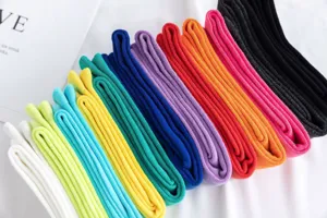 Nahaufnahme von bunten Baumwollsocken in Bonbonfarben, ordentlich in hellen Tönen aufgereiht.