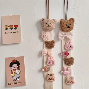 Close-up of cute plush bear and bunny hair clip organizer straps hanging on a wall.
