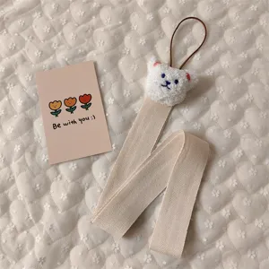 Macro detail of cute white plush bear on a beige woven hair accessory storage strap