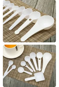 Set aus weißen Kunststoff-Messlöffeln in verschiedenen Größen auf einer Matte