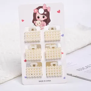 Detailed view of 6-piece set of mini pearl-studded bag-shaped hair claws on card