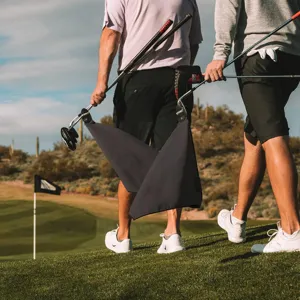 Magnetic microfiber golf towel attached to a golf club on a green field scene