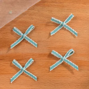 Primo piano di quattro piccoli fiocchi blu decorativi con bordi sfrangiati per abiti